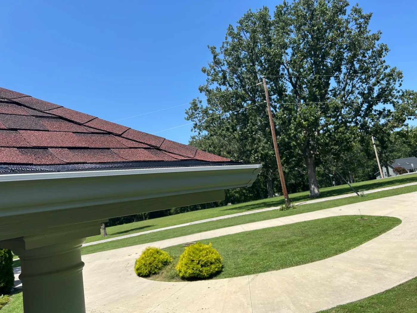 Gutter guard installed beneath an asphalt shingle roof edge