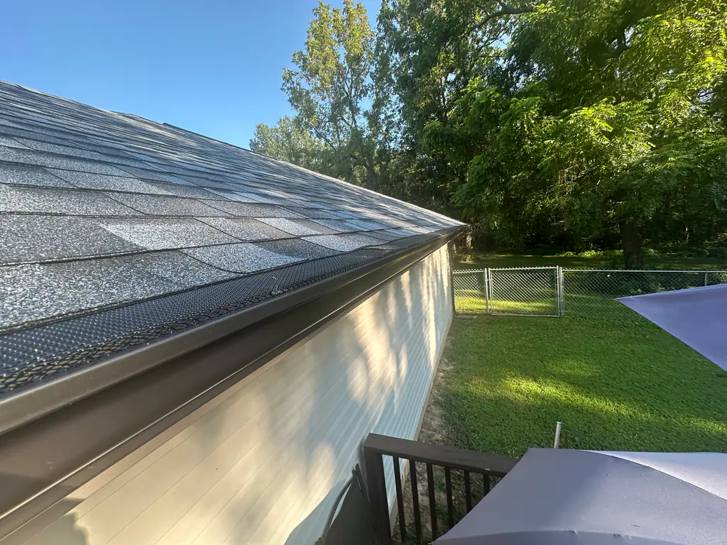 New gutter and gutter guard installed along an asphalt shingle roof
